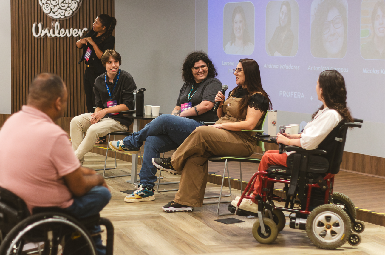Pessoas participando de um painel em ambiente corporativo da Unilever, sentadas em cadeiras no palco, com uso de microfone.
