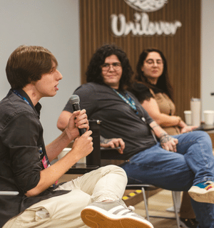 Participantes de um painel corporativo sentados em cadeiras durante uma conversa em um escritório da Unilever. Uma pessoa fala ao microfone enquanto outras acompanham a discussão.