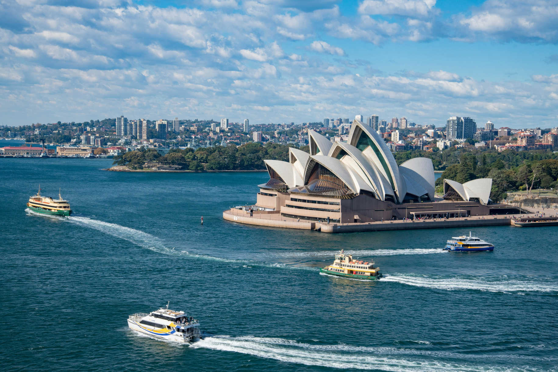 Ferries sailing near a modern waterfront opera house