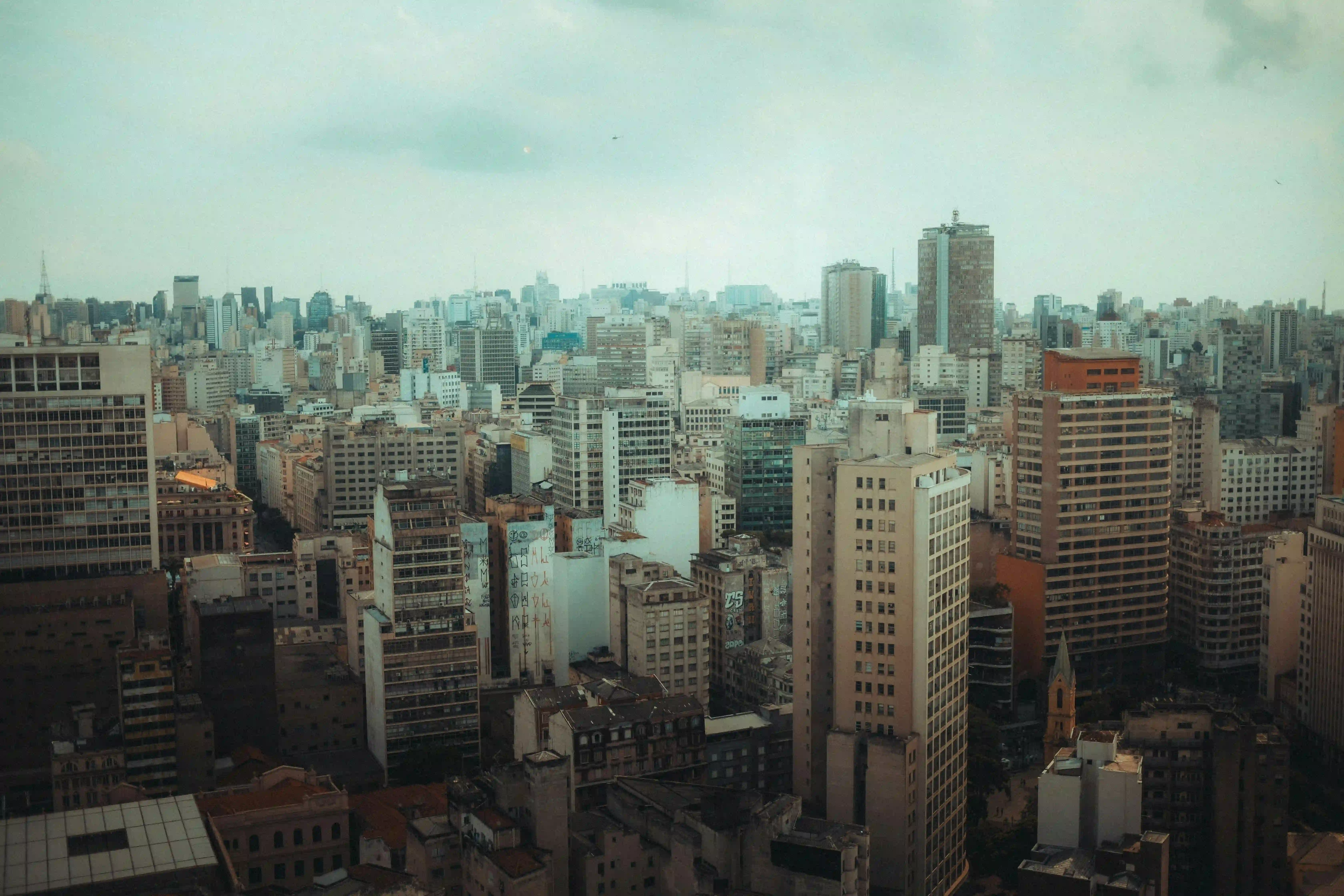 Dense city skyline with tall buildings under cloudy sky.