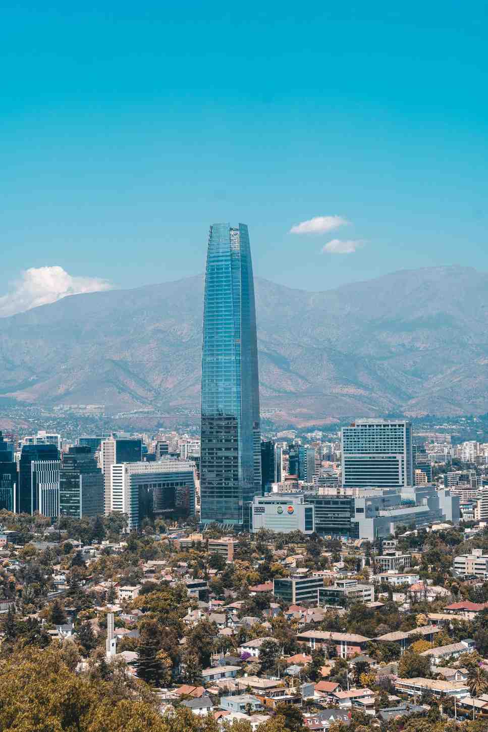 Tall modern skyscraper with city and mountains behind