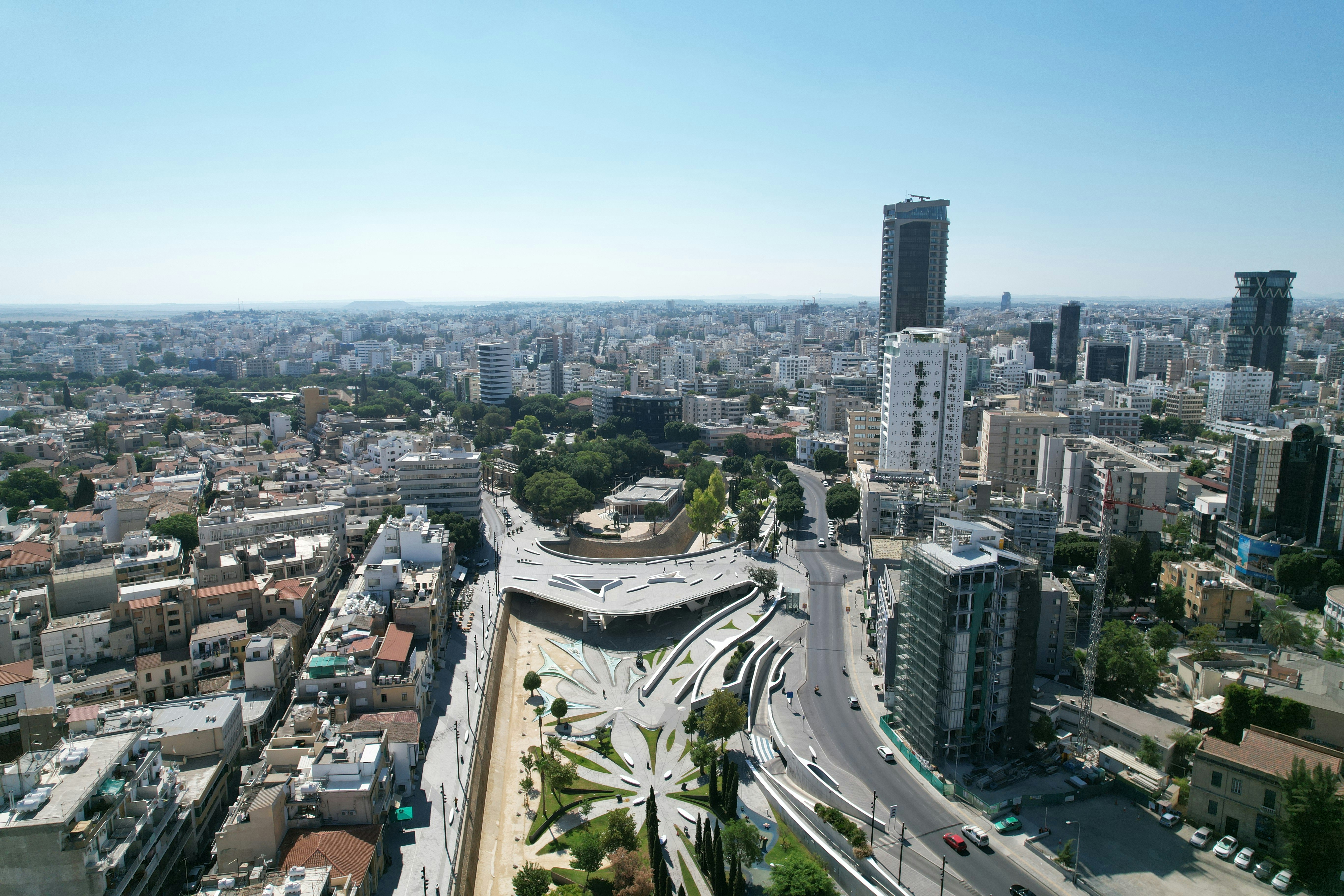 Aerial view of a cityscape with dense buildings and a modern park featuring geometric paths