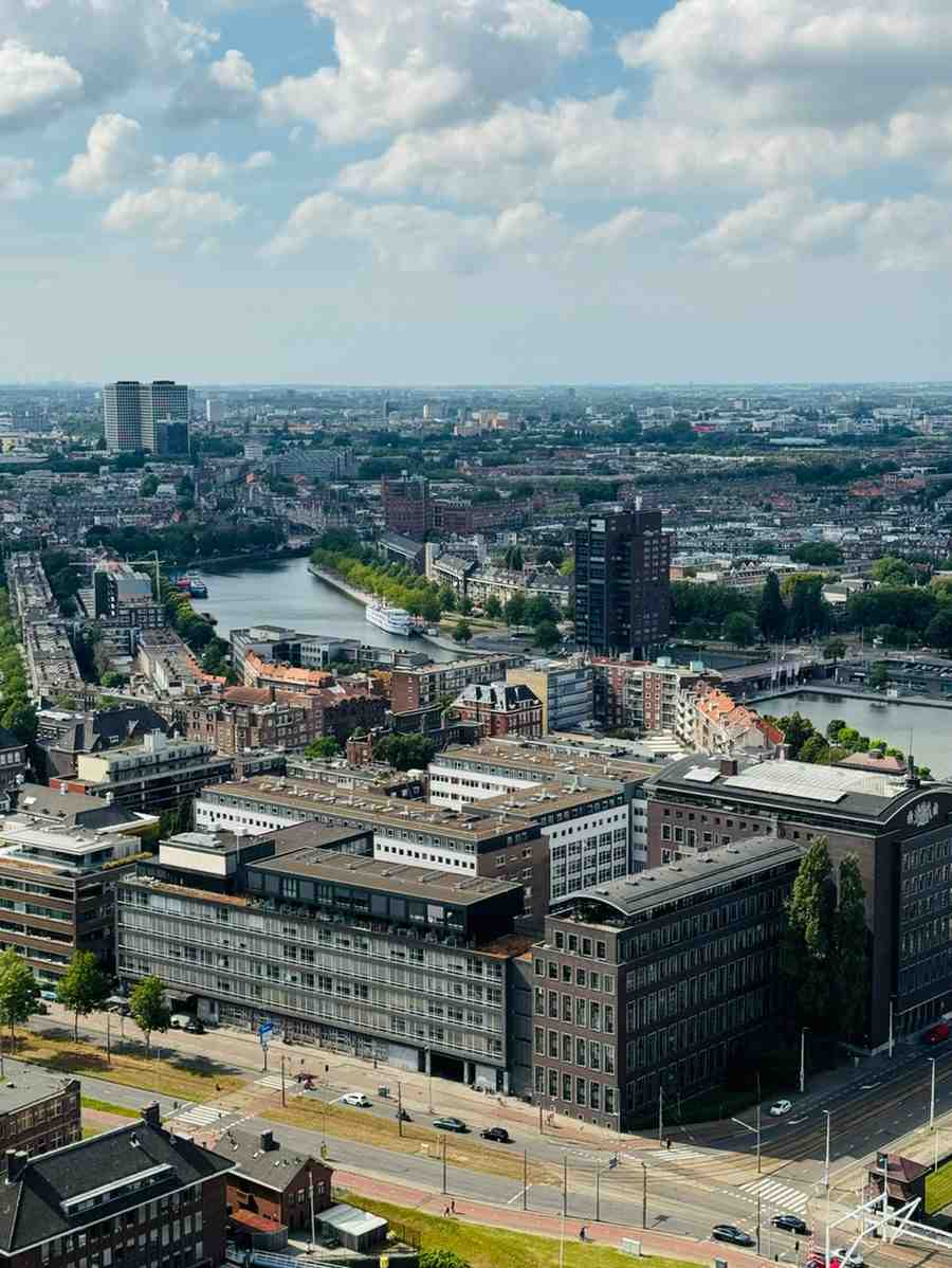 Cityscape with river, buildings, and cloudy blue sky.