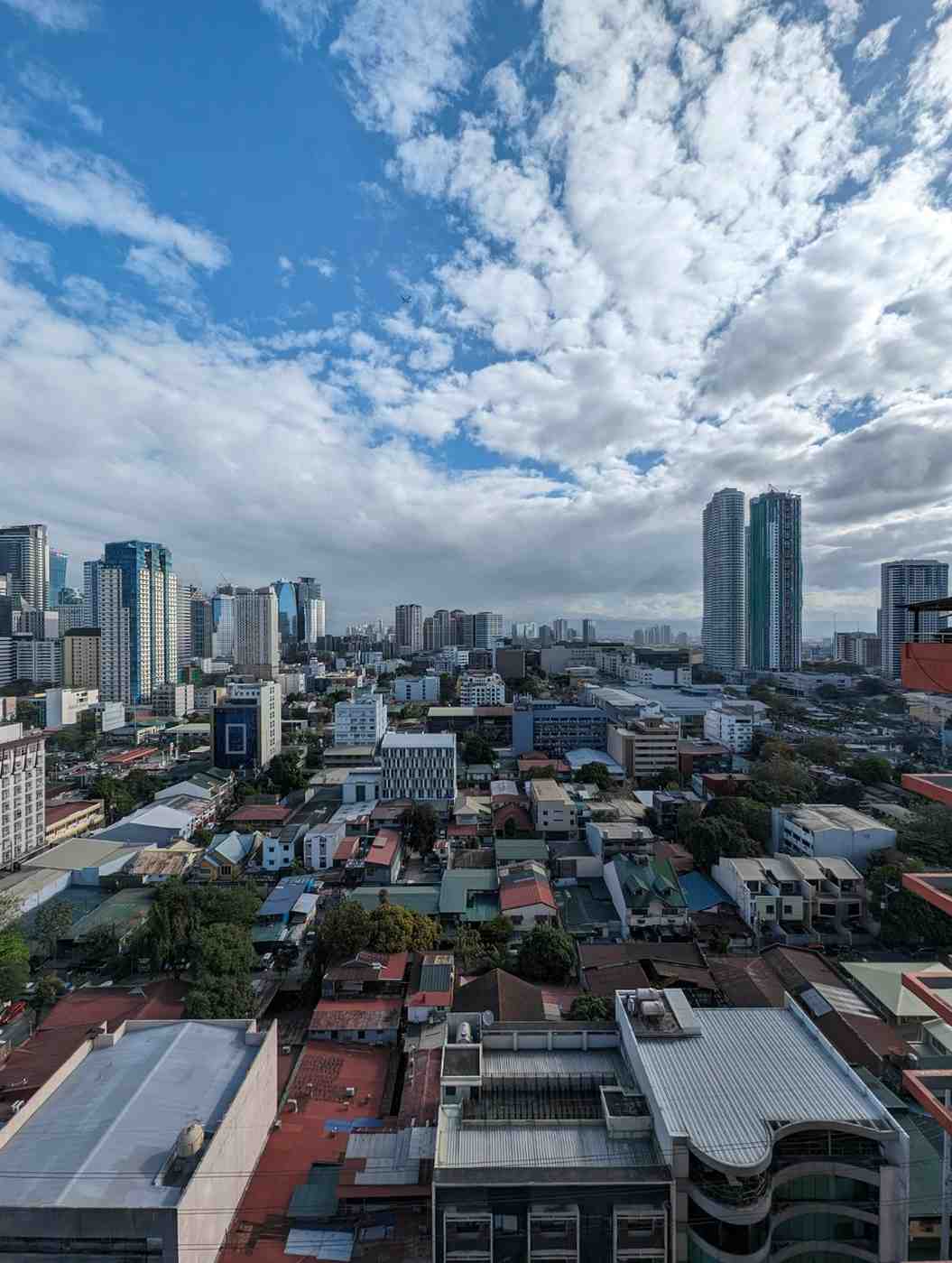 Cityscape with tall buildings under a partly cloudy sky.