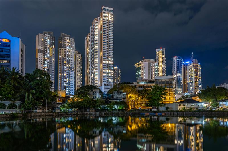 City skyline at night with lights reflecting on water.