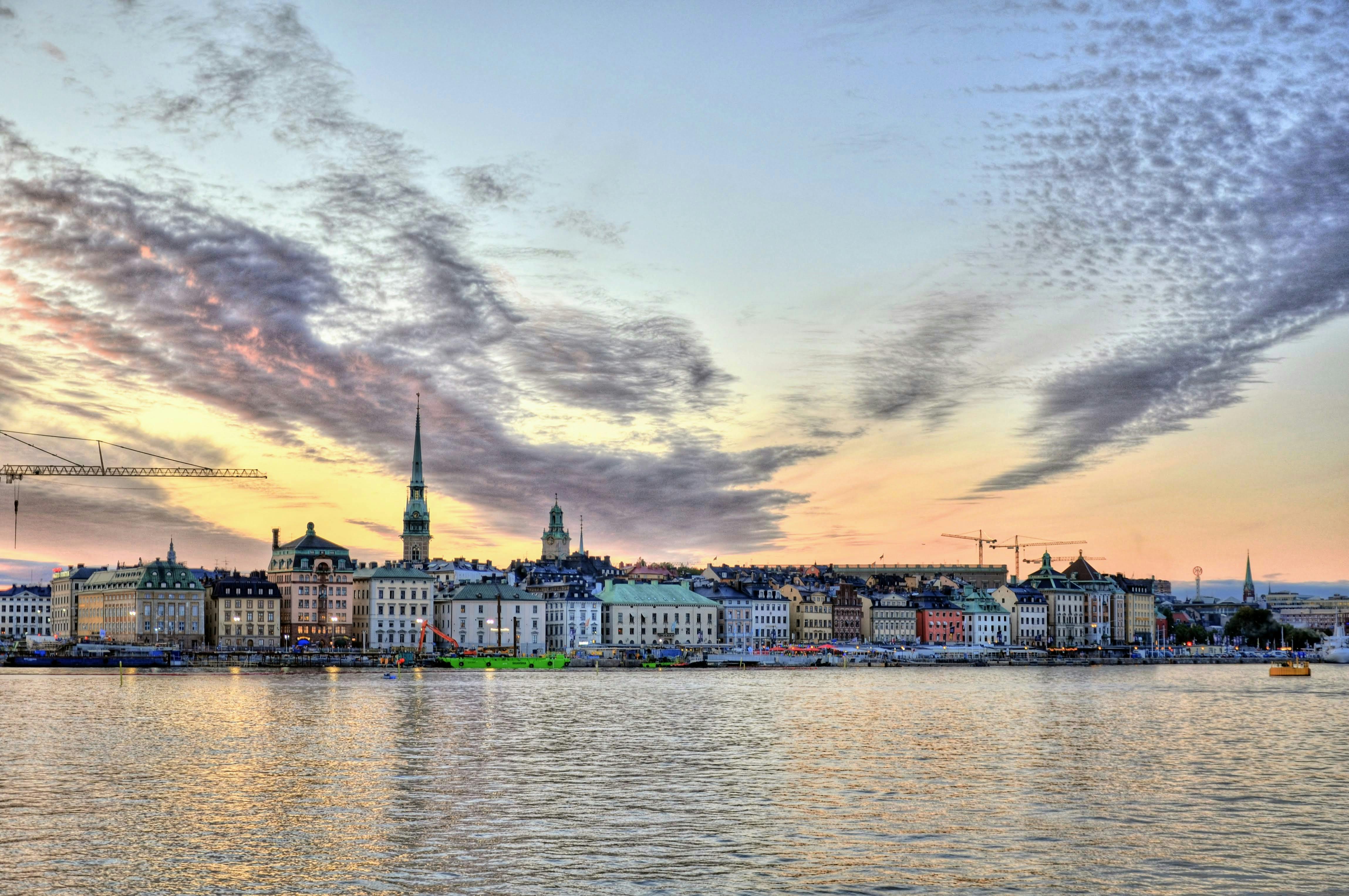 Panoramic view of colorful waterfront buildings and church spires at sunset reflected on the water