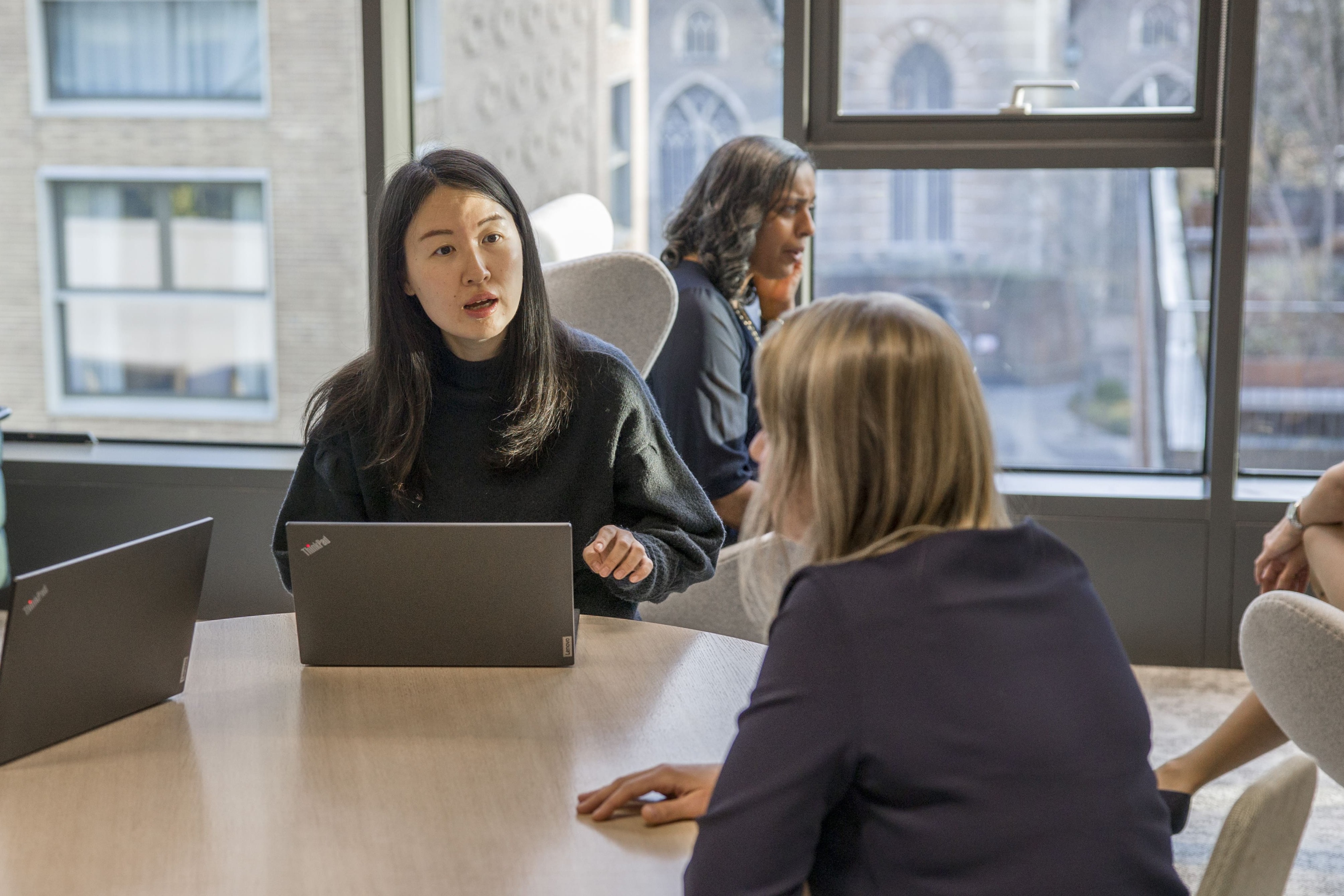 Two people in conversation at a table in a modern office environment.