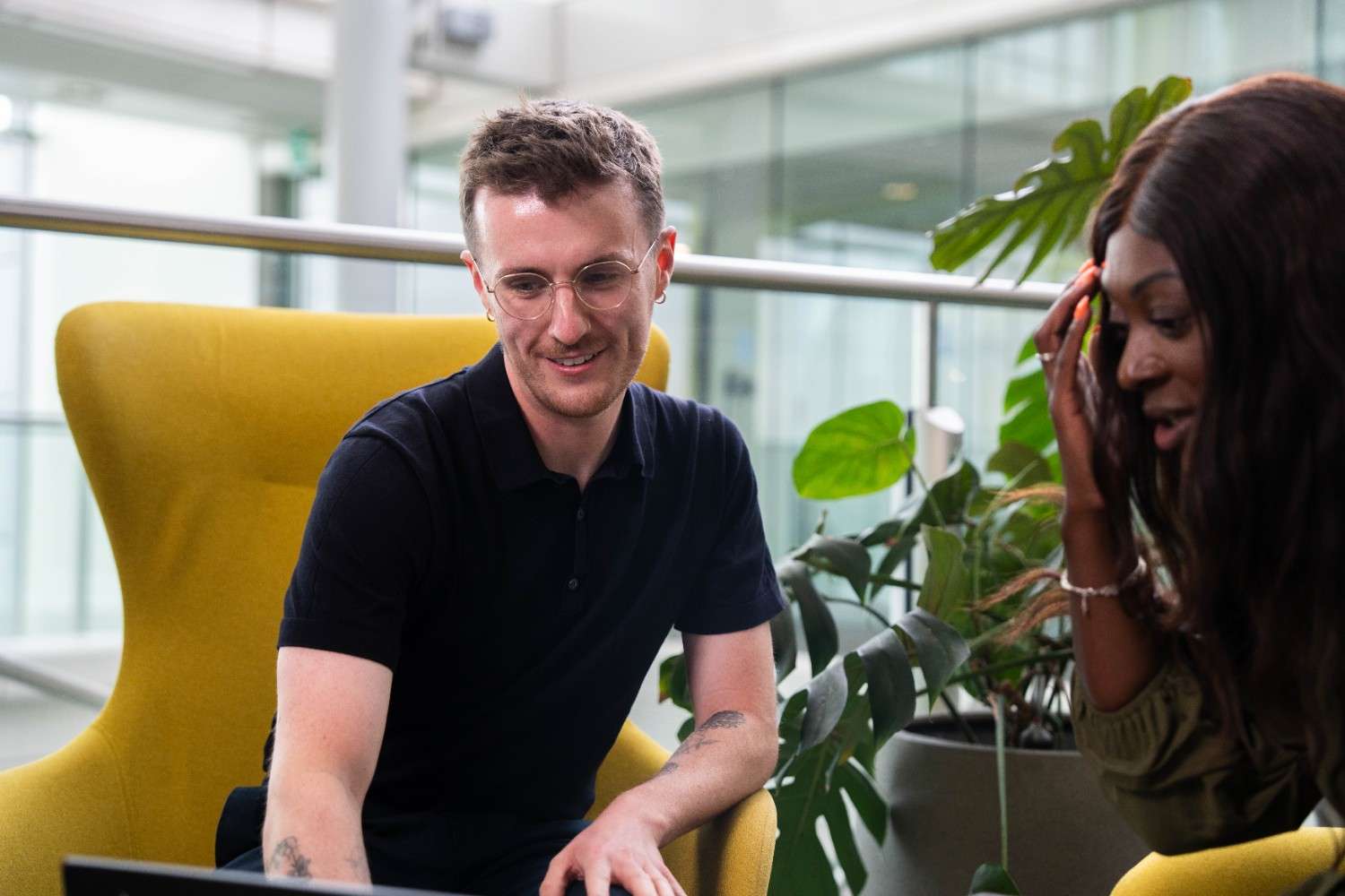 Two colleagues smiling while looking at a laptop.