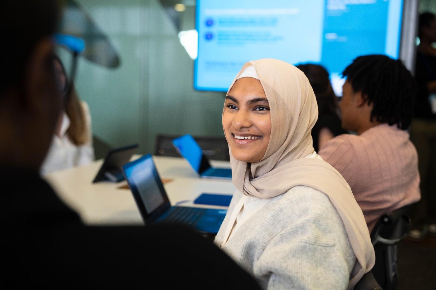 Smiling woman in hijab during a meeting with laptops