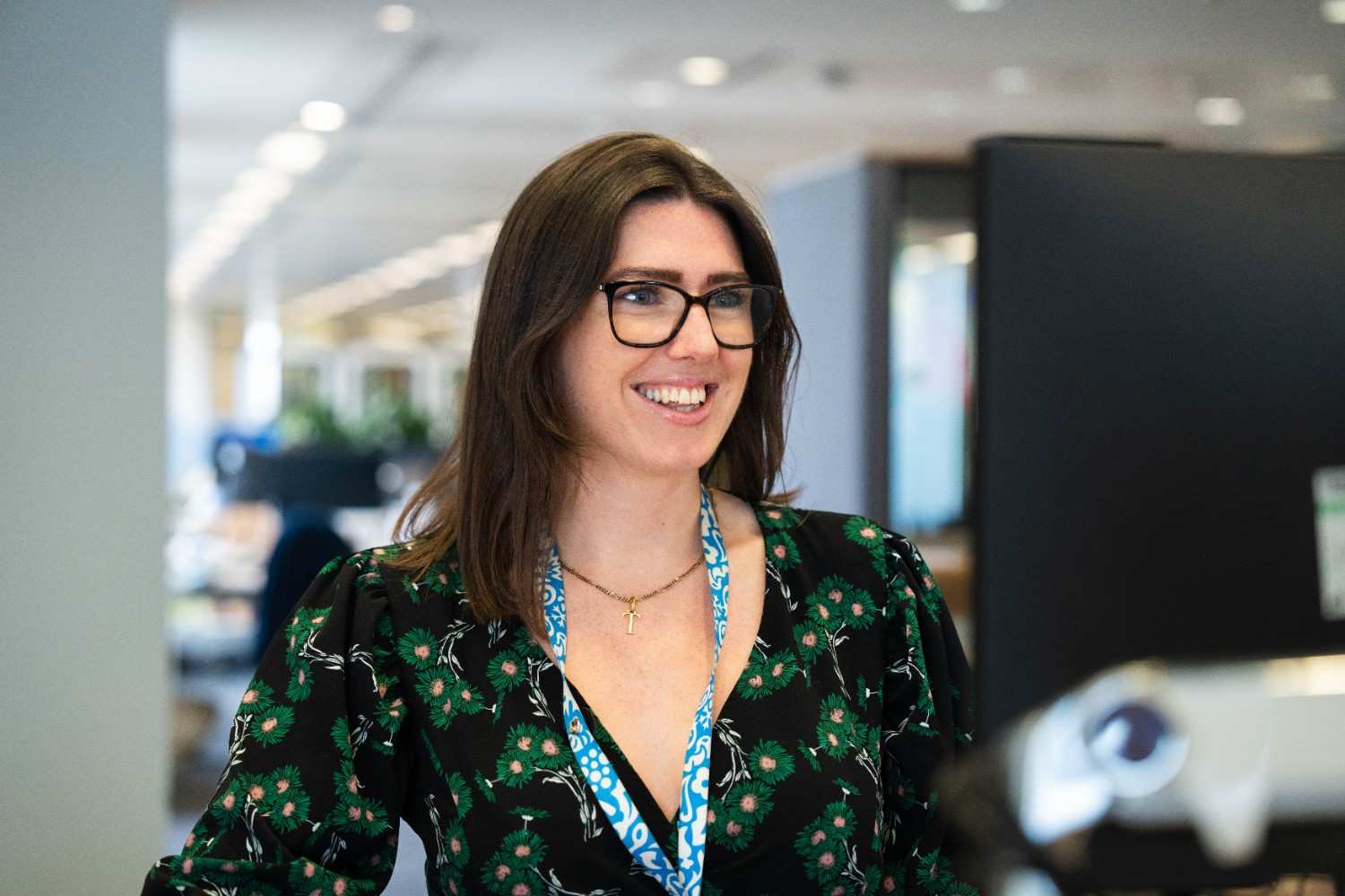 Smiling woman with glasses working at a desk.