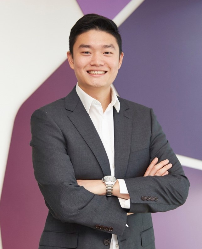 Smiling man in a suit with arms crossed.
