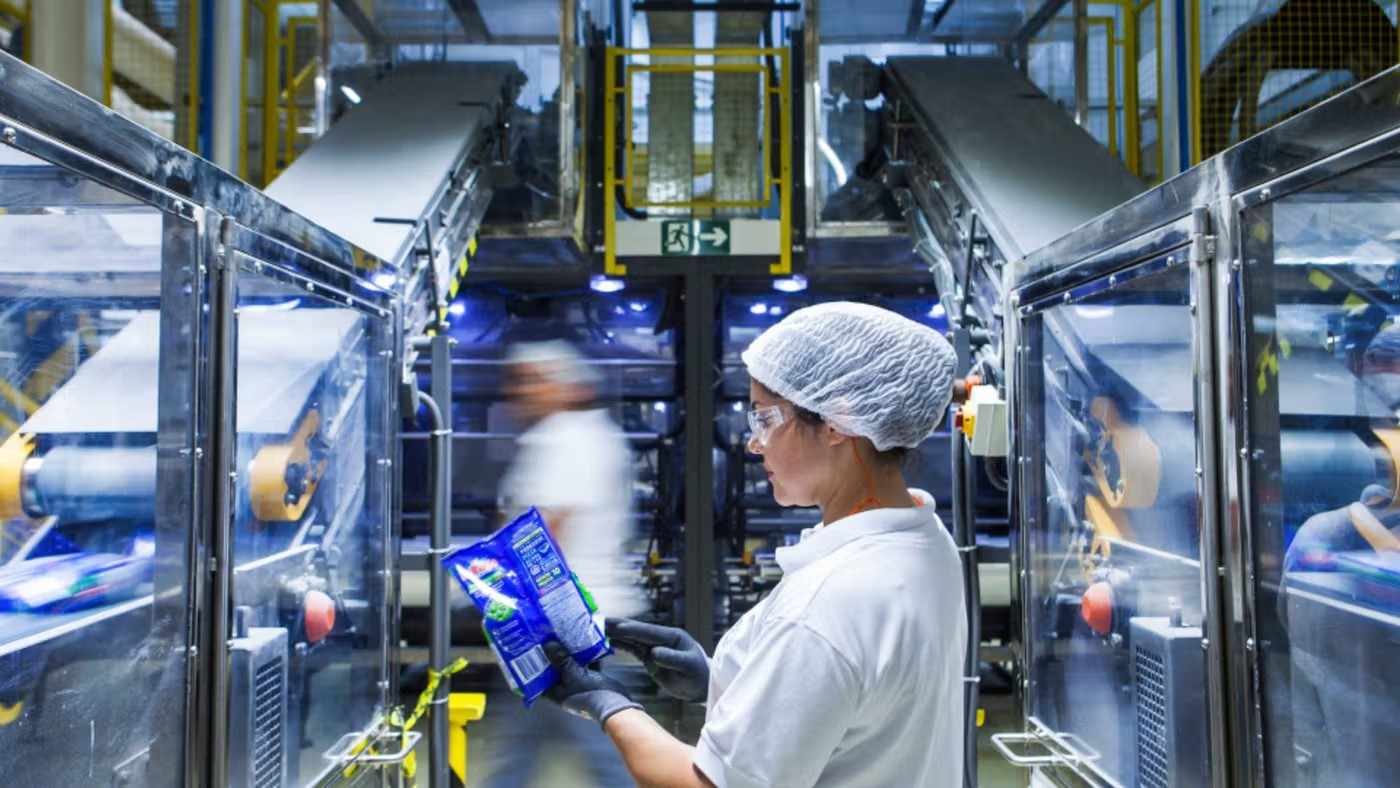 Worker inspecting packaged products on factory line