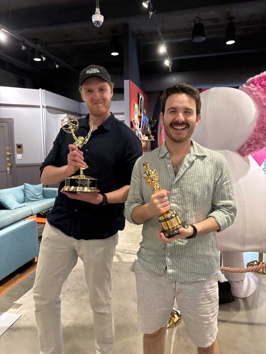 Two members of the Unilever creative team holding award statuettes on a film set.
