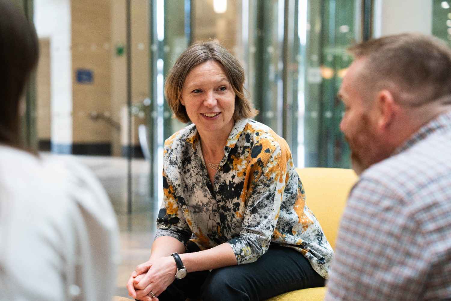 Woman smiling while talking with colleagues indoors