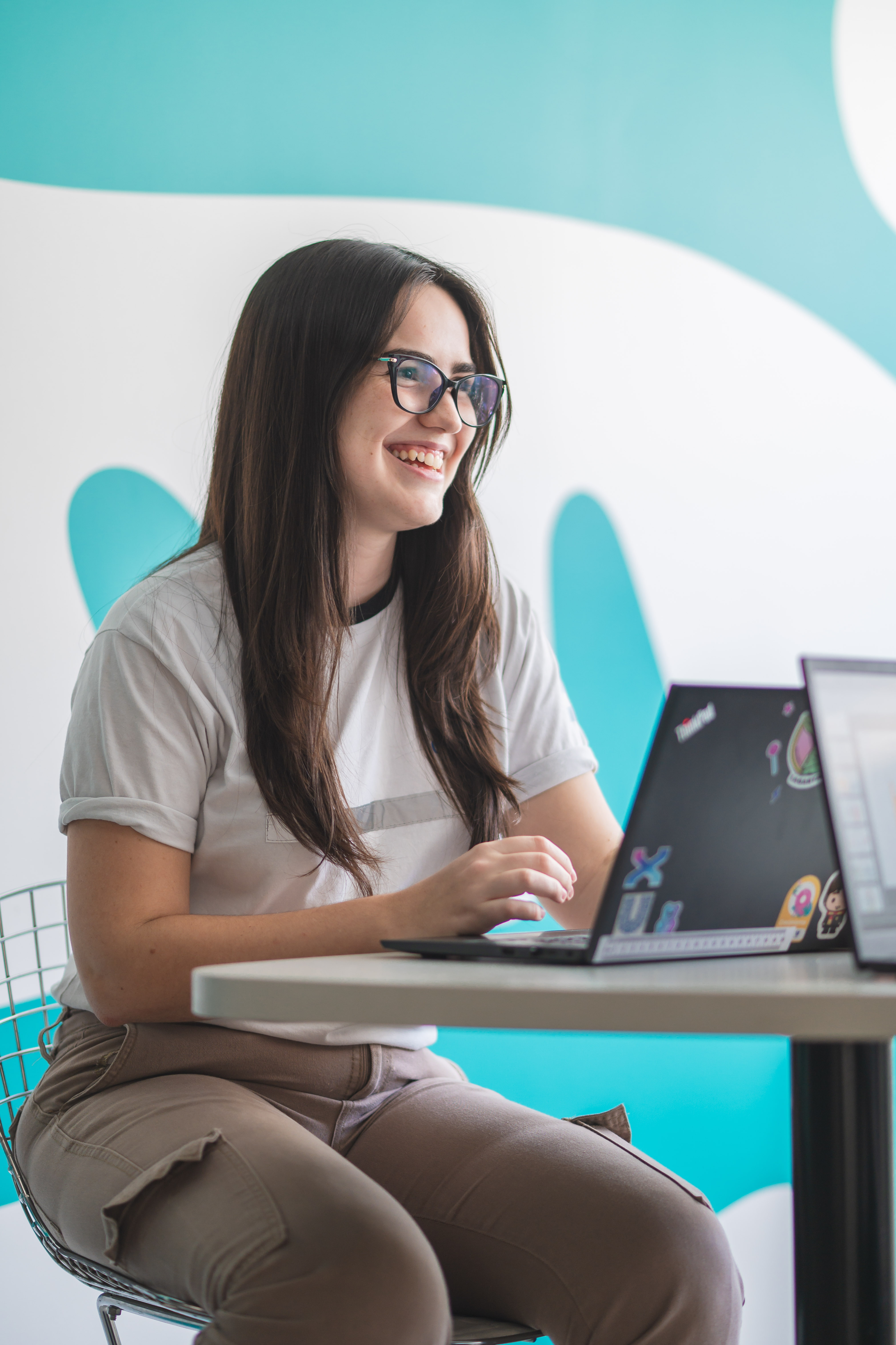 Woman in t-shirt looking at laptop in front of a light blue and white background