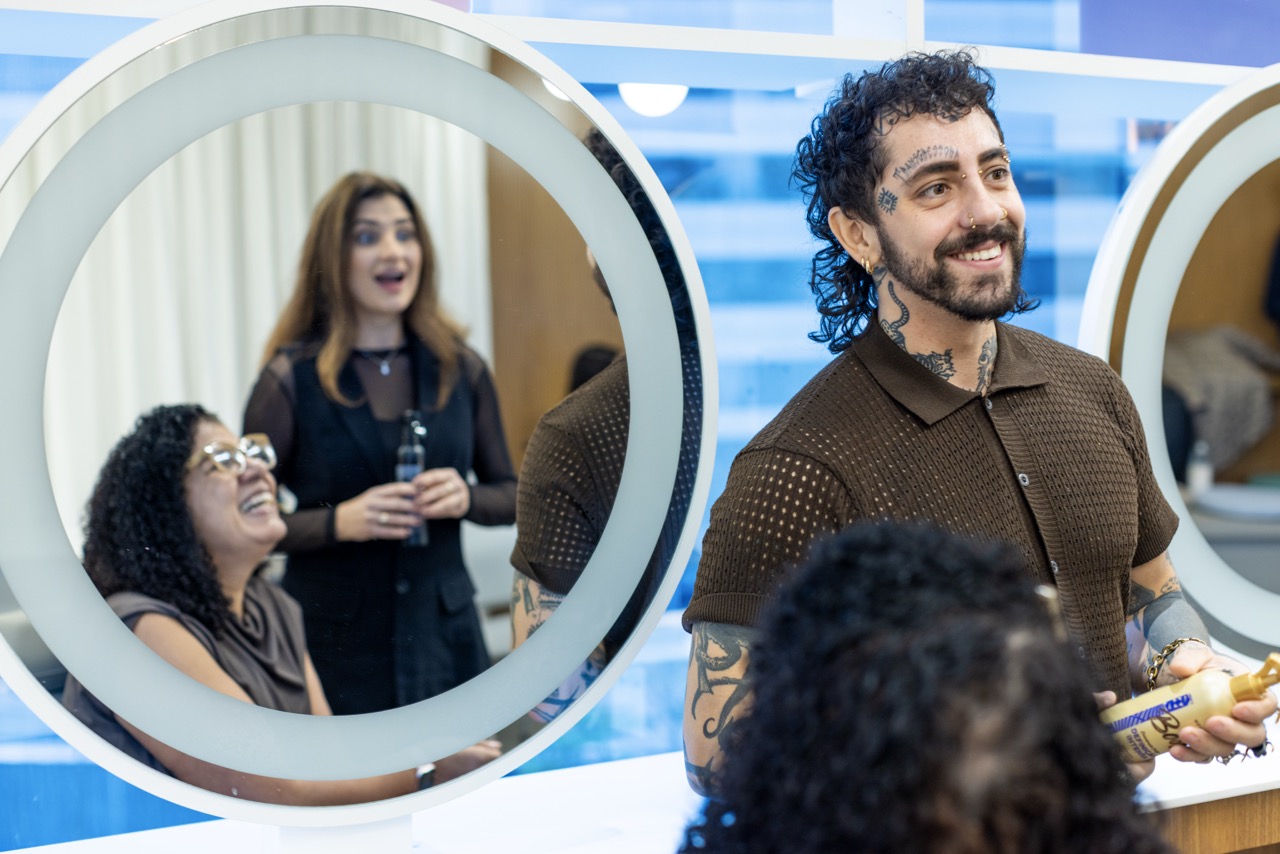 Colleagues chat and laugh together in a bright Unilever office, with one colleague holding a personal care product beside illuminated mirrors.