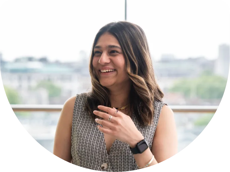 young employee smiling at a large window in office space