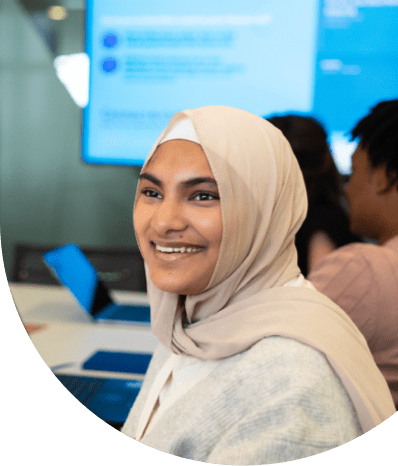 Professional seated at a conference table with laptops and a presentation screen in a modern office setting