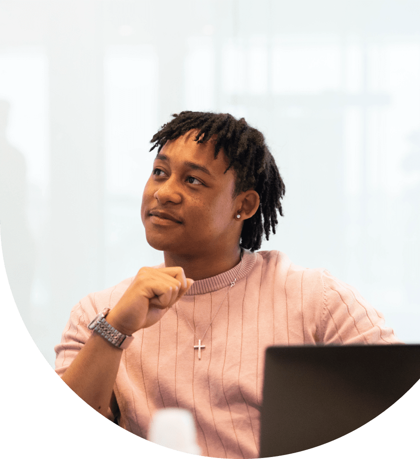 Professional seated at a desk with a laptop in a modern office, appearing focused and engaged in thought