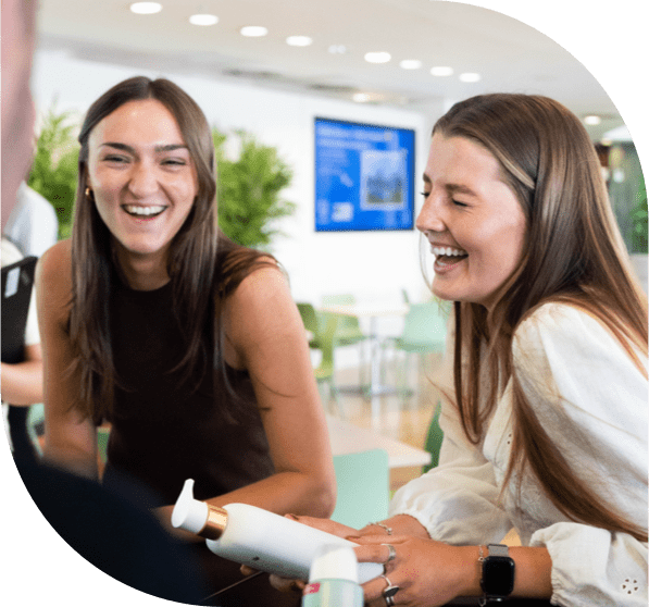 two individuals holding unilever products, discussing and laughing in a modern office
