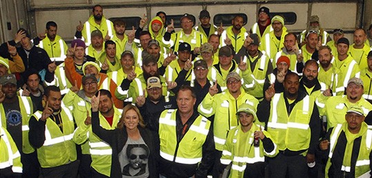 Group photo of Waste Connections employees with hands in the air