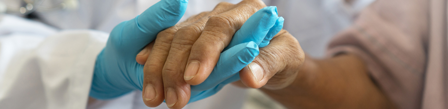Pfleger hält Hand des Patienten. 