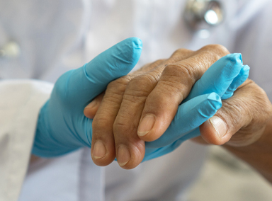 Pfleger hält Hand des Patienten.