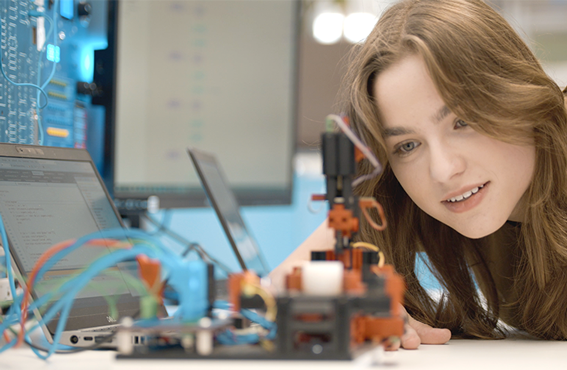 Woman looking closely at constructed items connected to computers