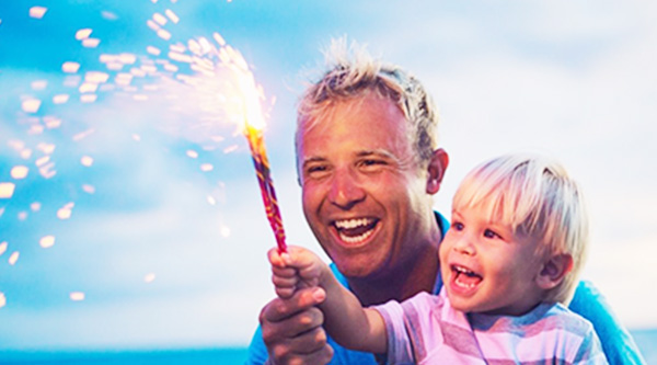 Dad smiling with kid as they hold flare