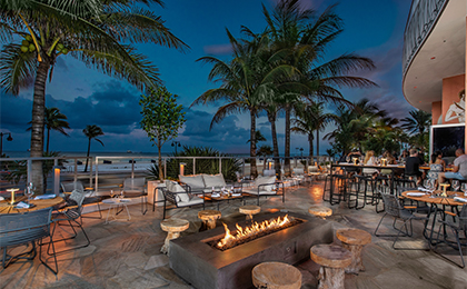 Outdoor patio behind restaurant with fire pits and palm trees