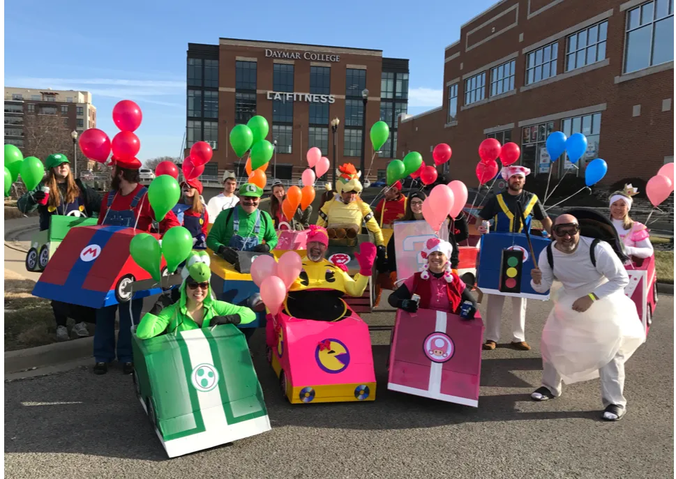 Group in cardboard race car costumes with balloons at an outdoor event