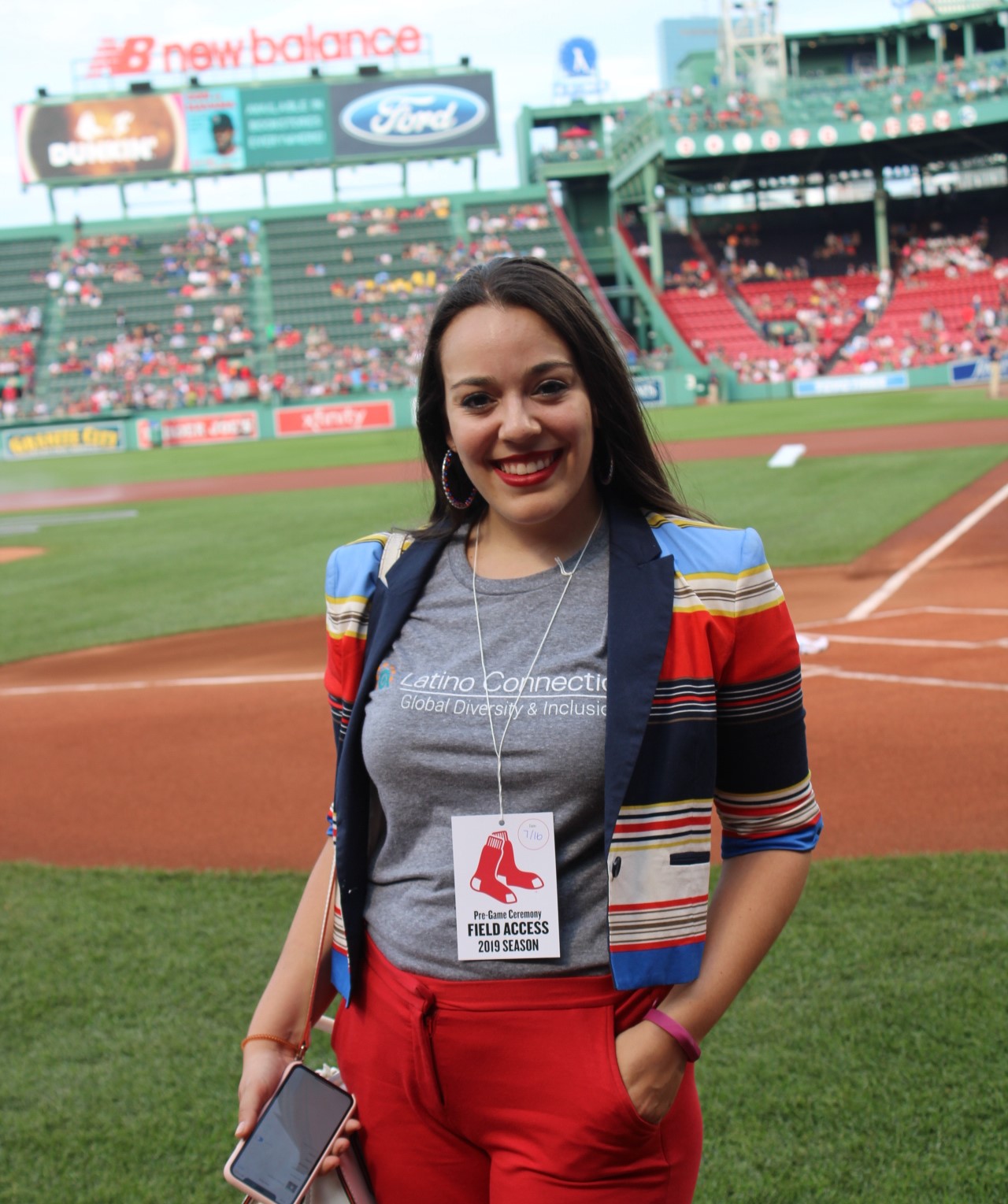 Gabriela poses on the field at a Red Sox baseball game in a Latino Connection t-shirt.