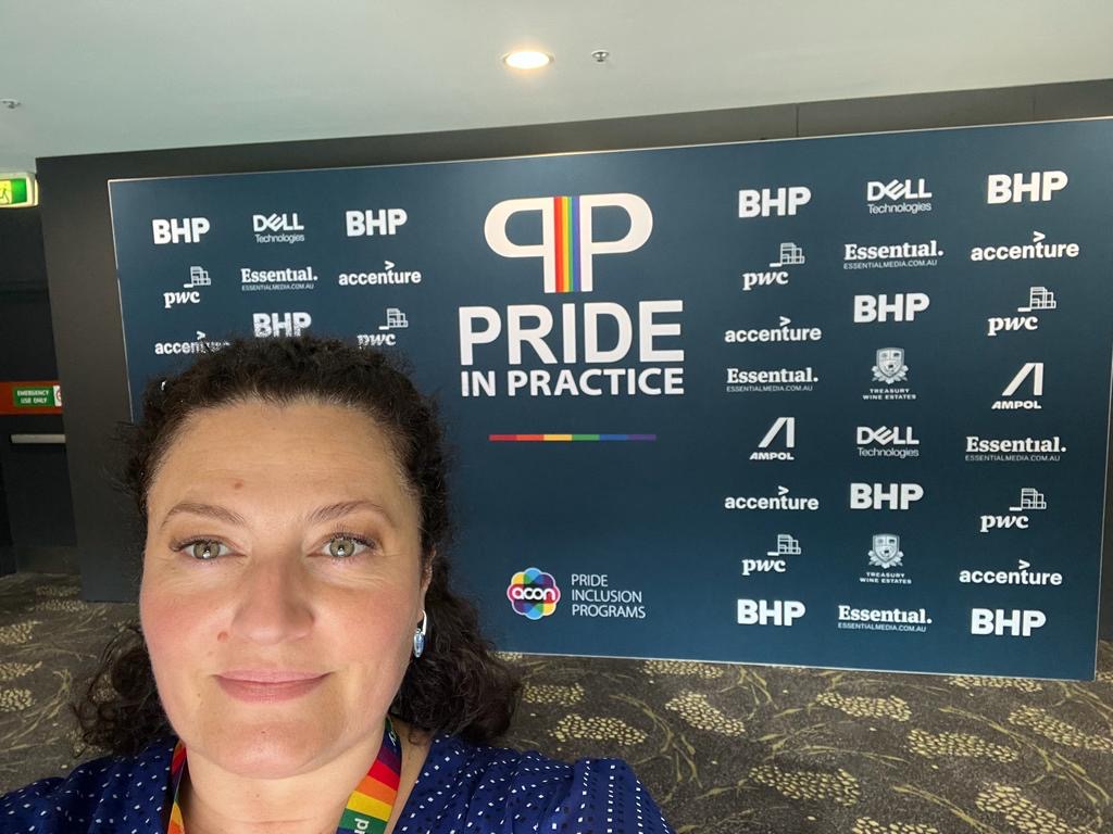 Clelia smiles in front of a Dell Technologies Pride ERG event banner.