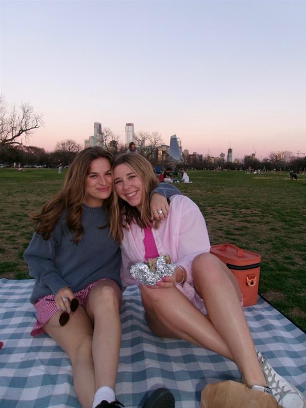 Macy and a friend pose on a picnic blanket.