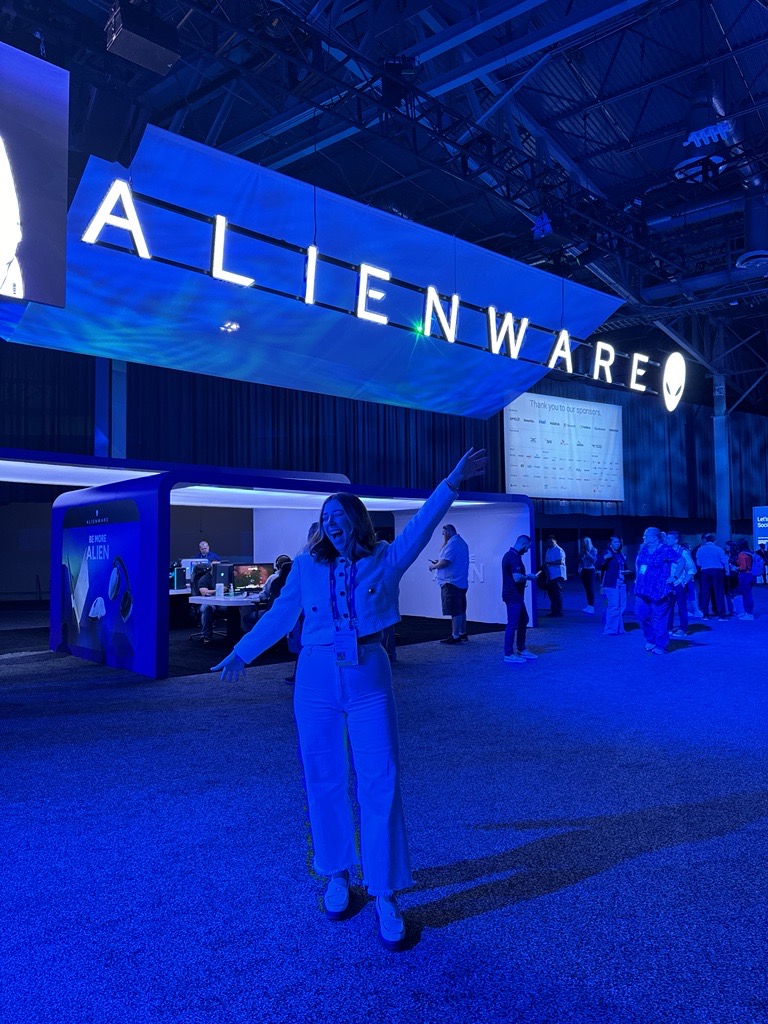 Macy poses at Dell Technologies World in front of the Alienware booth.