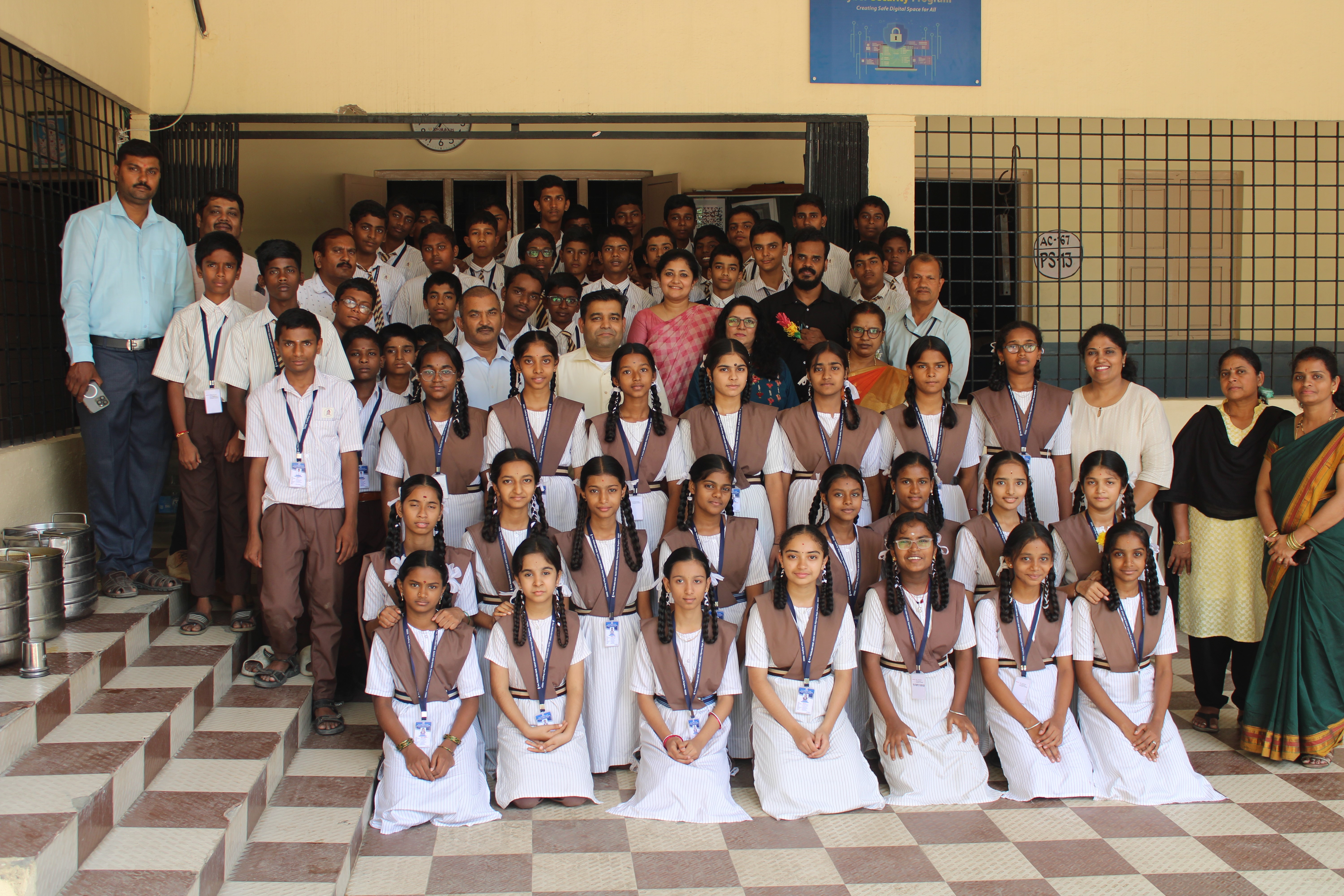 A group of school children and adults smile together.