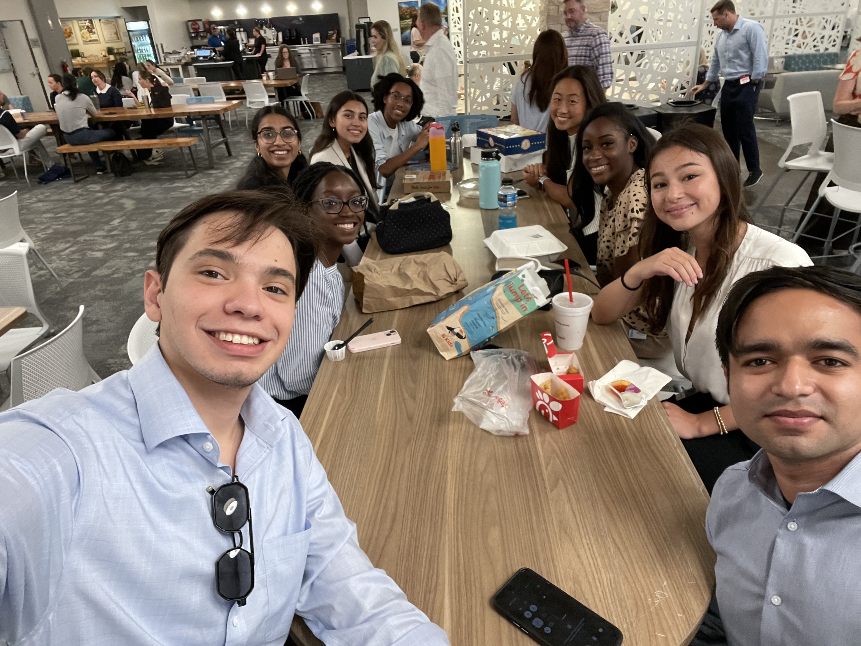 Sebastian poses with other interns while sitting at a table in the cafeteria.