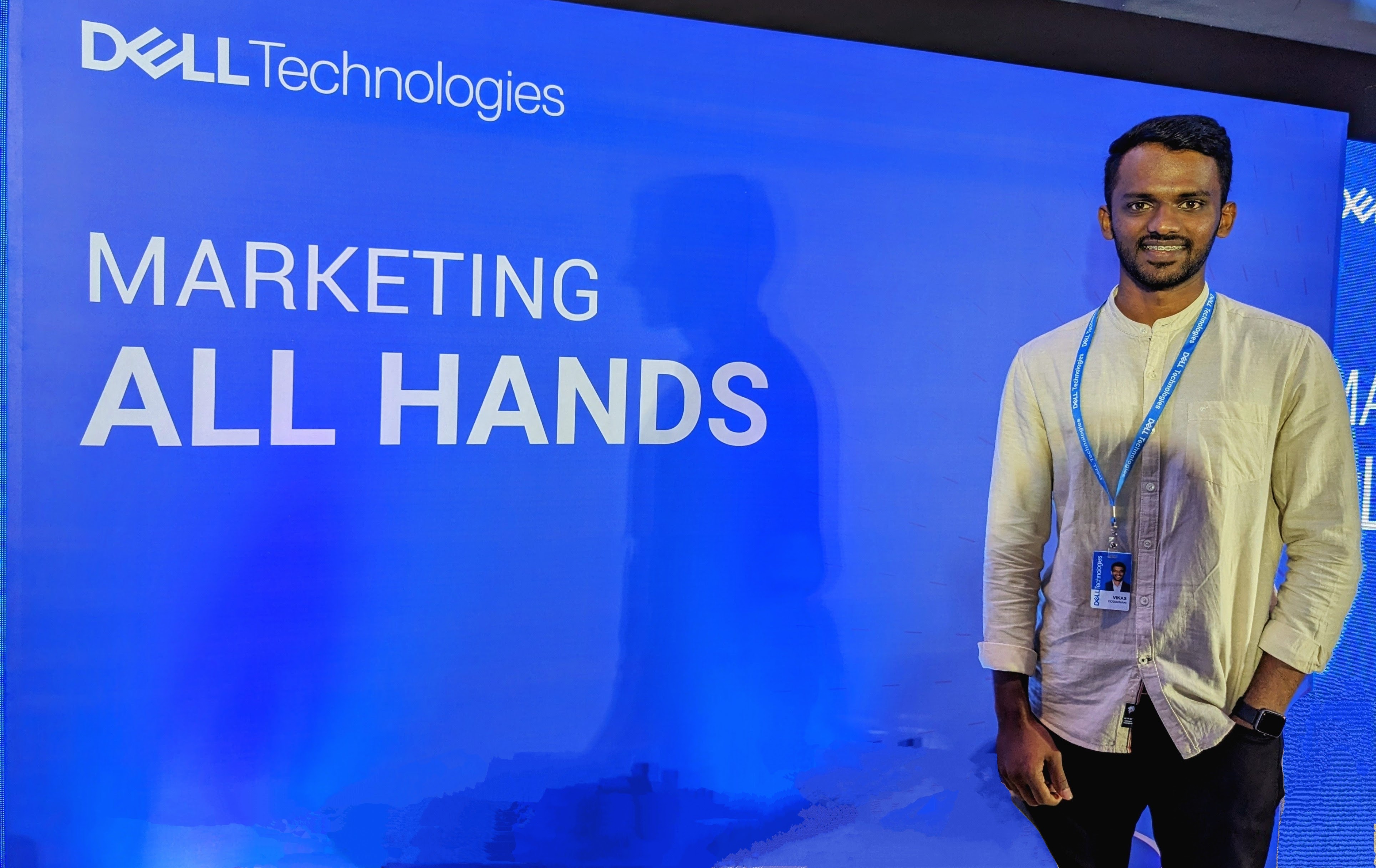 Vikas stands in front of a sign for a marketing all hands meeting.