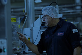 Man wearing hairnet and protective goggles opearting a machine