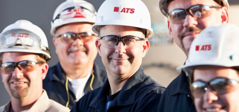 Group of people wearing white hard hats with the ATS logo on them
