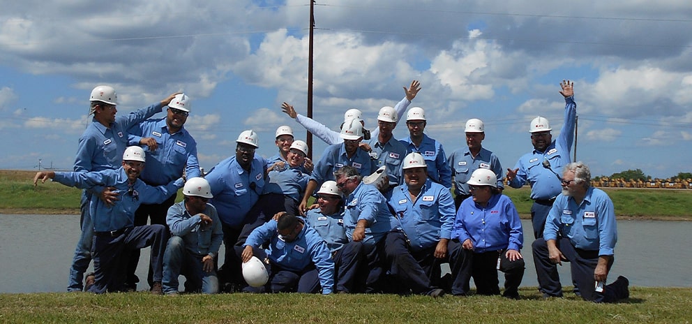 Large group of men in blue shirts and white hard hats