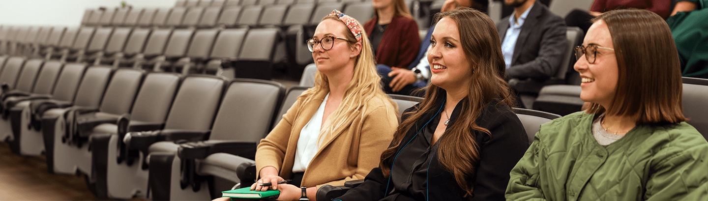 Three female students, sitting in a lecture auditorium