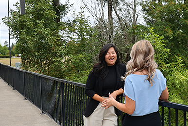 Three women walking outside through a wooded park