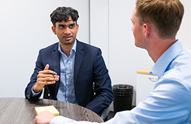 Two professionals discussing work at a meeting table.
