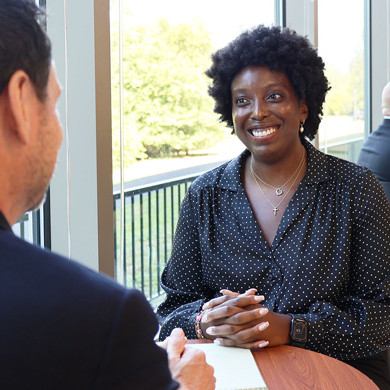 A woman, seated at a at a table having a one on one meeting