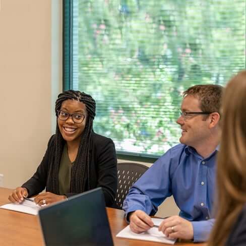 African-American female employee smiling while talking with other employees