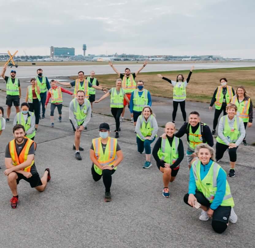 Airport personnel on a tarmac posing for photo