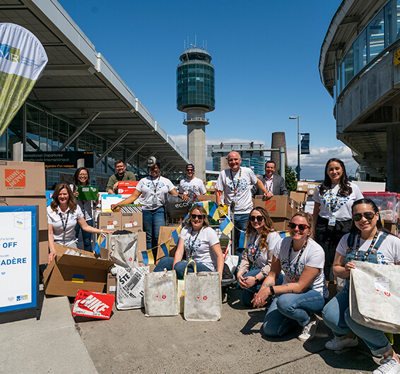 Multiple men and women posing outside next to an airport terminal