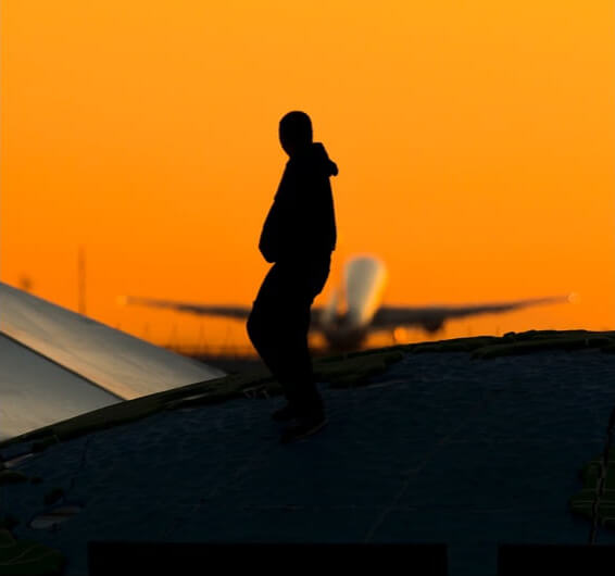 Man walking at sunset with airplane in the background