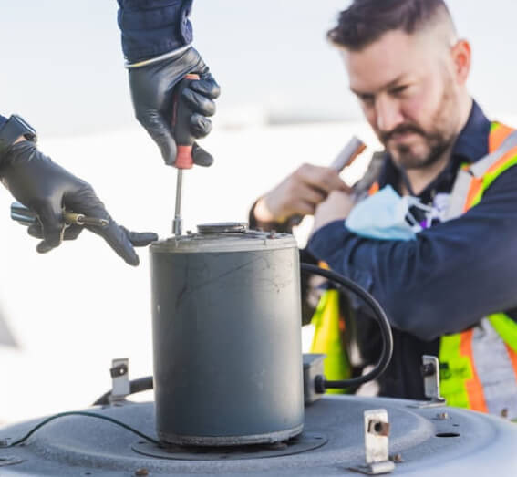 Employés masculins effectuant la maintenance d'une pièce de moteur d'avion